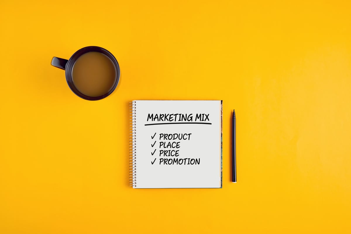 The word marketing mix written on notebook with pen and coffee mug
